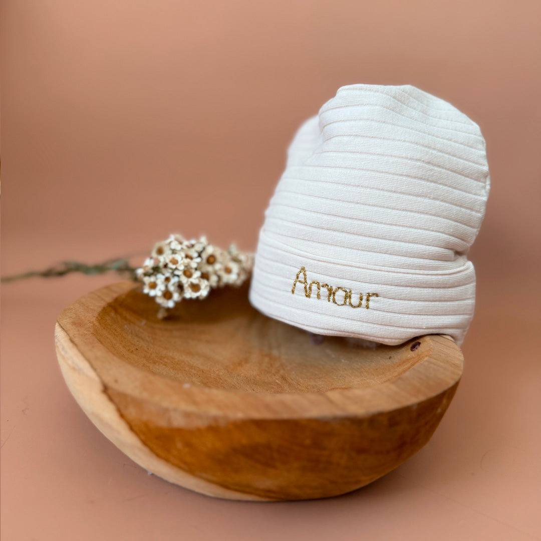 Le bonnet de naissance personnalisé pour bébé en maille côtelée est l'accessoire idéal pour les premiers jours de votre nouveau-né. Confectionné avec soin dans un jersey de coton côtelé , ce bonnet offre à votre bébé douceur et confort incomparables. Il est fabriqué dans l’un de nos ateliers partenaires français. Nous conseillons ce modèle de bonnet plus léger pour les naissances prévues de mai à septembre.  Un cadeau parfaitement adapté pour accueillir votre petit trésor dans le monde avec tendresse et dou