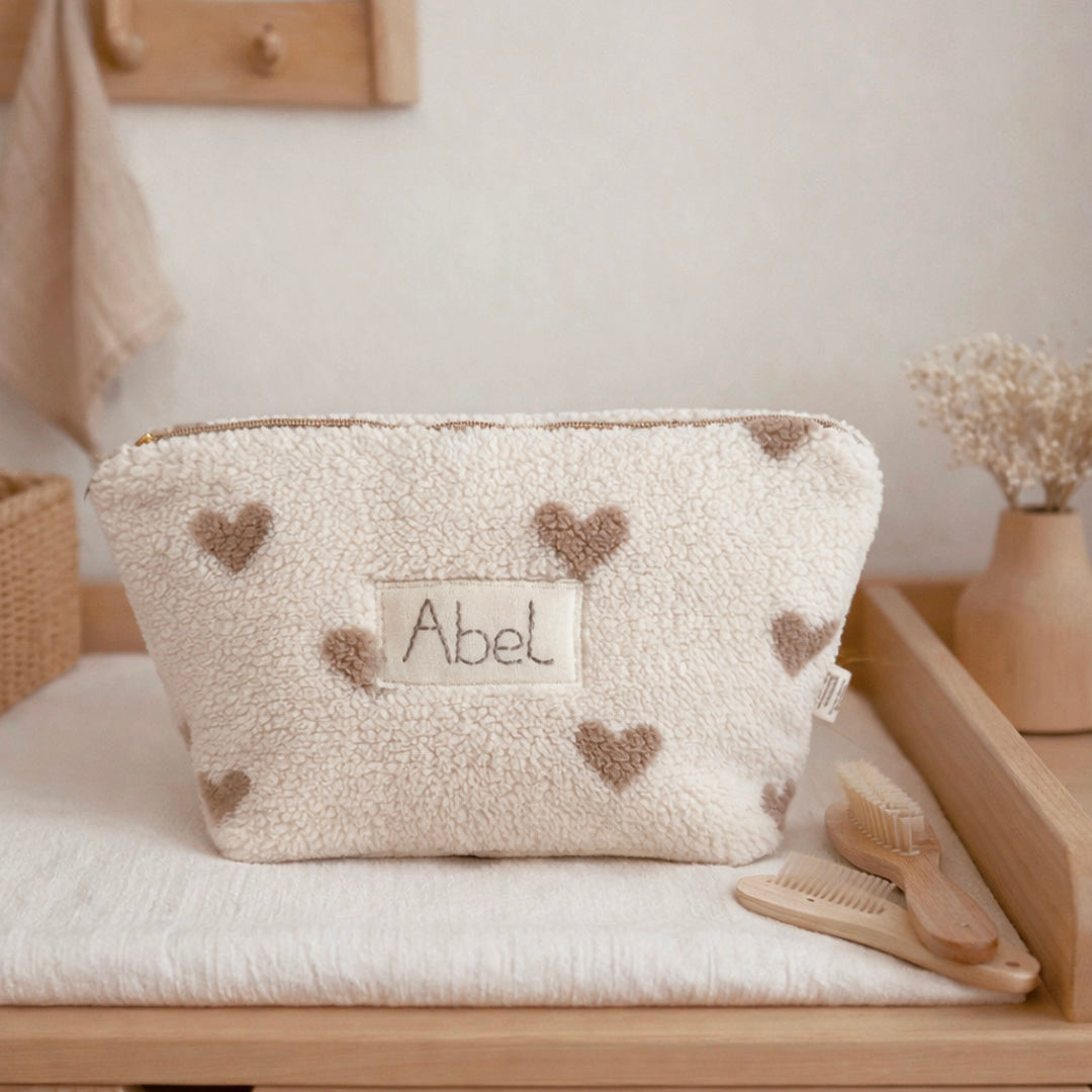 La trousse de toilette pour bébé est une pièce personnalisée et pratique, conçue avec soin pour répondre aux besoins des parents et de leur nouveau-né. Son grand format est très pratique.  La conception de la trousse permet aux produits de bébé de tenir debout à l'intérieur, ce qui facilite l'organisation et l'accès aux produits essentiels. Liniment, couches, lait de toilette, cotons, autant de produits pour un si petit bout de chou, que vous aurez besoin d'une grande trousse de toilette spacieuse. Fabriqué