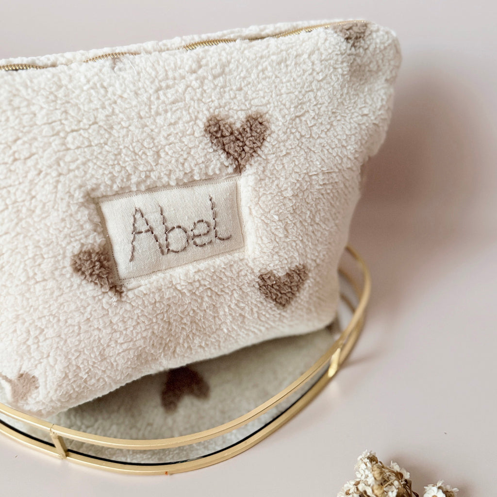 La trousse de toilette pour bébé est une pièce personnalisée et pratique, conçue avec soin pour répondre aux besoins des parents et de leur nouveau-né. Son grand format est très pratique.  La conception de la trousse permet aux produits de bébé de tenir debout à l'intérieur, ce qui facilite l'organisation et l'accès aux produits essentiels. Liniment, couches, lait de toilette, cotons, autant de produits pour un si petit bout de chou, que vous aurez besoin d'une grande trousse de toilette spacieuse. Fabriqué