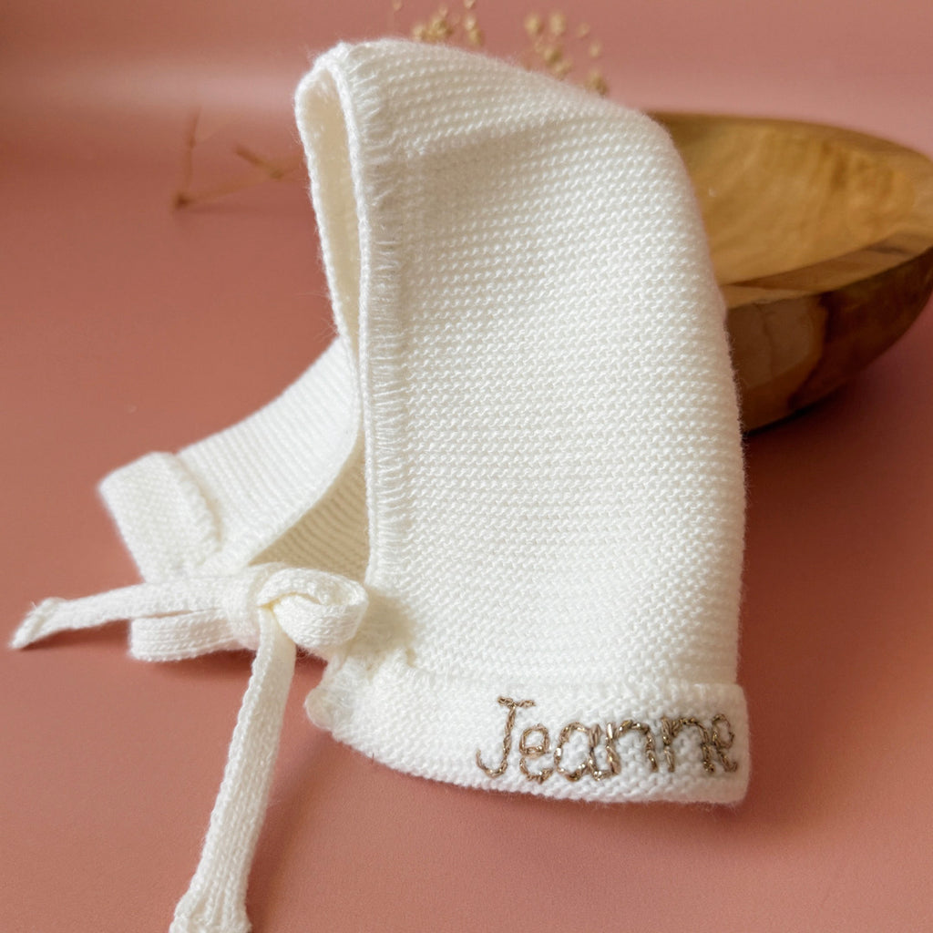 Le petit béguin de naissance, un incontournable dans la valise maternité Délicatement tricotée dans une douce laine alpaga écru, ce petit béguin respire l'élégance et la délicatesse, parfait pour les premiers jours de votre nouveau-né. Ce béguin peut être personnalisé avec le prénom de votre bébé, ajoutant une touche personnelle. Offrez à votre enfant un accessoire à la fois pratique et chargé d'émotion, idéal pour immortaliser ces précieux moments. Un cadeau parfaitement adapté pour accueillir votre petit 