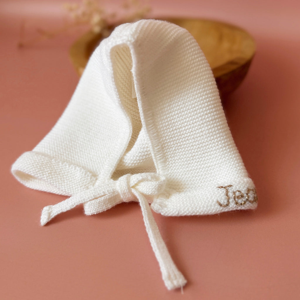 Le petit béguin de naissance, un incontournable dans la valise maternité Délicatement tricotée dans une douce laine alpaga écru, ce petit béguin respire l'élégance et la délicatesse, parfait pour les premiers jours de votre nouveau-né. Ce béguin peut être personnalisé avec le prénom de votre bébé, ajoutant une touche personnelle. Offrez à votre enfant un accessoire à la fois pratique et chargé d'émotion, idéal pour immortaliser ces précieux moments. Un cadeau parfaitement adapté pour accueillir votre petit 