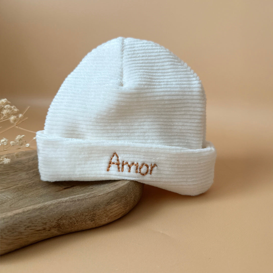 Le bonnet de naissance personnalisé pour bébé en maille velours côtelé est l'accessoire idéal pour les premiers jours de votre nouveau-né. Confectionné avec soin dans une maille éponge côtelée , ce bonnet offre à votre bébé douceur et confort incomparables. Il est fabriqué dans l’un de nos ateliers partenaires français. Un cadeau parfaitement adapté pour accueillir votre petit trésor dans le monde avec tendresse et douceur. Retrouvez dans la même gamme, nos petits chaussons de naissance. Grâce à sa texture,
