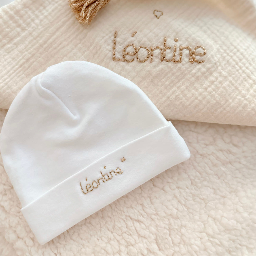 Immortaliser les premiers jours de vie de bébé avec ce joli petit bonnet personnalisé. Il est en 100% jersey de coton biologique écru. Il sera réchauffer bébé. Idéale pour annoncer le prénom de bébé à la naissance ! Le saviez-vous? Toutes les extrémités du corps de bébé sont les plus vulnérables au froid , pieds, mains, oreilles ... Même en plein été il est important de bien couvrir bébé dès la naissance, n'oublions pas qu'il sort d'un bain de 37° C depuis 9 mois !