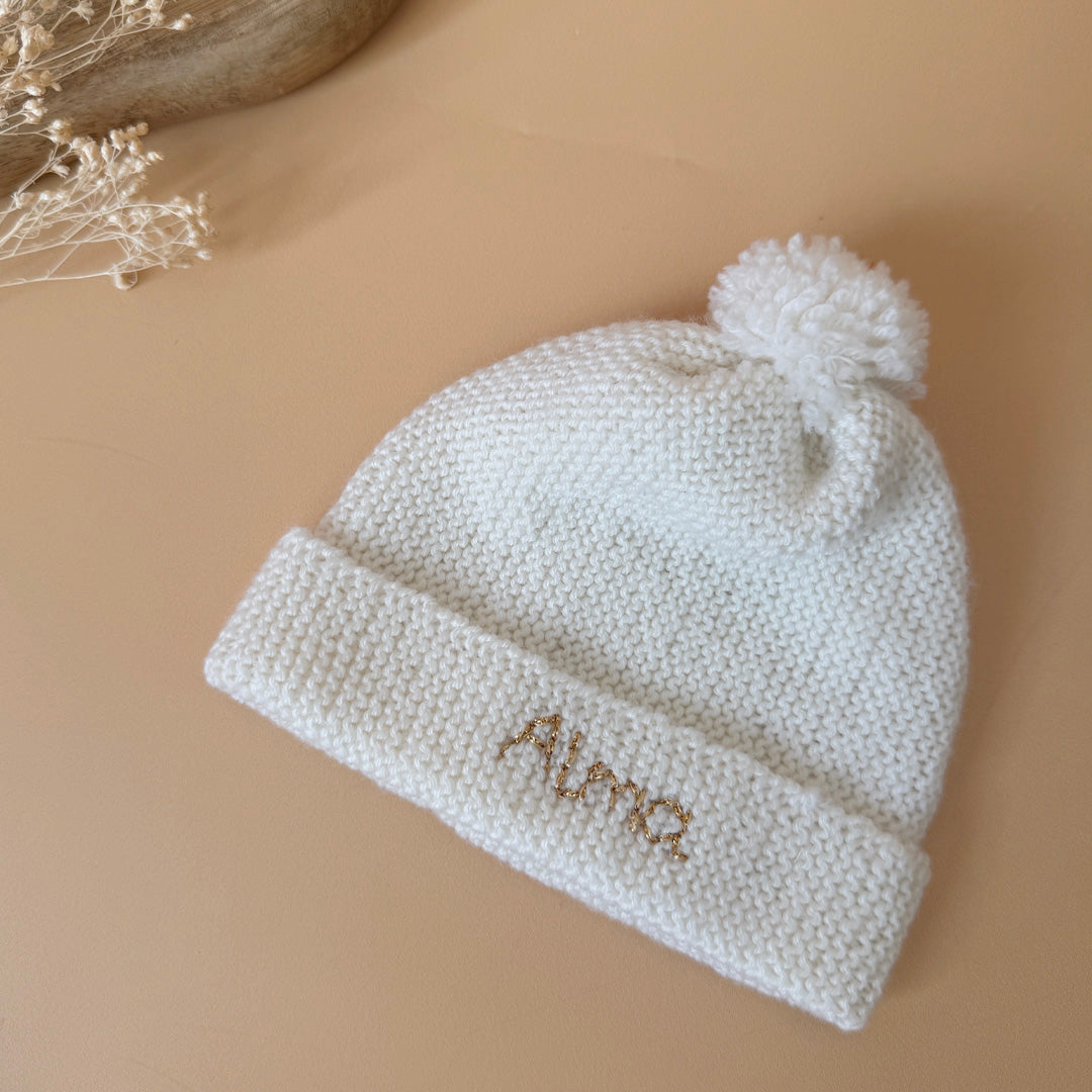 Le bonnet de naissance personnalisé pour bébé en maille tricotée de coton est l'accessoire idéal pour les premiers jours de votre nouveau-né. Confectionné avec soin, ce bonnet offre à votre bébé douceur et confort incomparables. Il est fabriqué dans l’un de nos ateliers partenaires français. Un cadeau parfaitement adapté pour accueillir votre petit trésor dans le monde avec tendresse et douceur. Retrouvez dans la même gamme, nos petits chaussons de naissance. Grâce à sa texture et à sa conception, ce bonnet