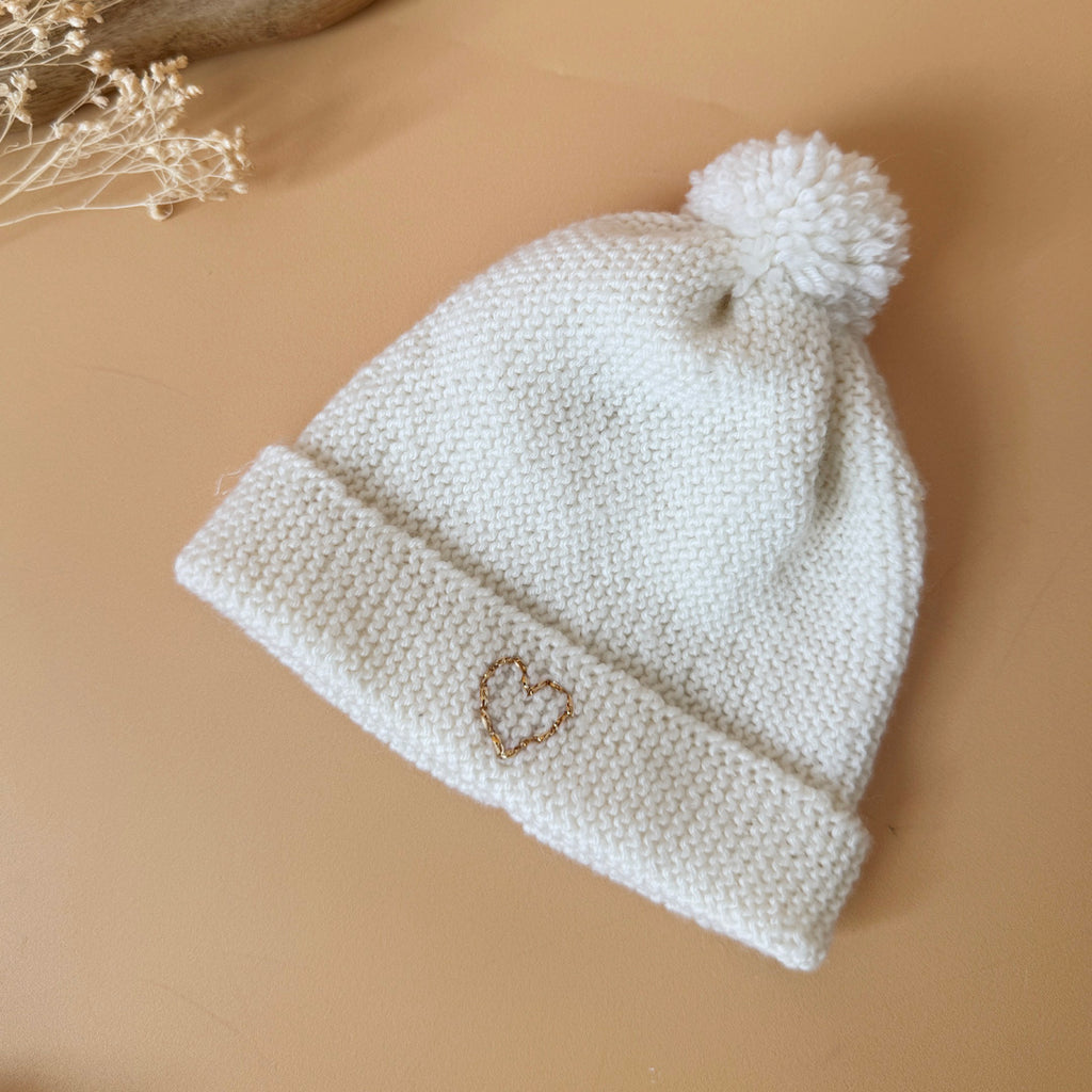 e bonnet de naissance personnalisé pour bébé en maille tricotée de coton est l'accessoire idéal pour les premiers jours de votre nouveau-né. Confectionné avec soin, ce bonnet offre à votre bébé douceur et confort incomparables. Il est fabriqué dans l’un de nos ateliers partenaires français. Un cadeau parfaitement adapté pour accueillir votre petit trésor dans le monde avec tendresse et douceur. Retrouvez dans la même gamme, nos petits chaussons de naissance. Grâce à sa texture et à sa conception, ce bonnet 