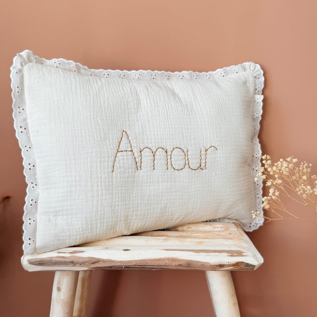 Offrez à la chambre de votre enfant une touche d'élégance et de douceur avec ce coussin rectangulaire très raffiné. Confectionné avec soin, il allie la gaze de coton et la maille de nid d'abeille grattée, des matériaux à la fois légers, aérés et agréables au toucher. Son coloris écru intemporel s'intégrera parfaitement dans tout type de décoration, apportant à la pièce une ambiance chaleureuse et apaisante. Ce coussin n'est pas seulement un accessoire de décoration, il devient aussi un objet personnalisé et