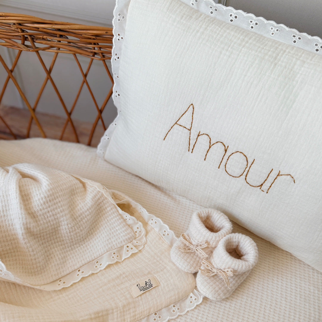 Offrez à la chambre de votre enfant une touche d'élégance et de douceur avec ce coussin rectangulaire très raffiné. Confectionné avec soin, il allie la gaze de coton et la maille de nid d'abeille grattée, des matériaux à la fois légers, aérés et agréables au toucher. Son coloris écru intemporel s'intégrera parfaitement dans tout type de décoration, apportant à la pièce une ambiance chaleureuse et apaisante. Ce coussin n'est pas seulement un accessoire de décoration, il devient aussi un objet personnalisé et