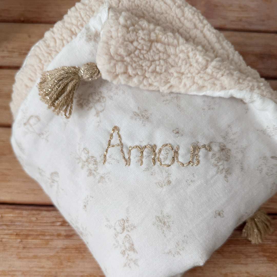 La couverture est une des pièces indispensable du trousseau de bébé. Parfaite en cadeau de naissance ou à s’offrir soit même, cette couverture demie saison est aprfaite pour accompagner bébé tout au long de l'année, Cette grande couverture pourra également être utilisée en descente de lit quand bébé sera plus grand. Cette couverture est idéale pour bien réchauffer les bébés en demie saison grâce à sa fausse fourrure type sherpa mouton beige , et sa doublure en gaze de coton hypoallergénique au magnifique mo