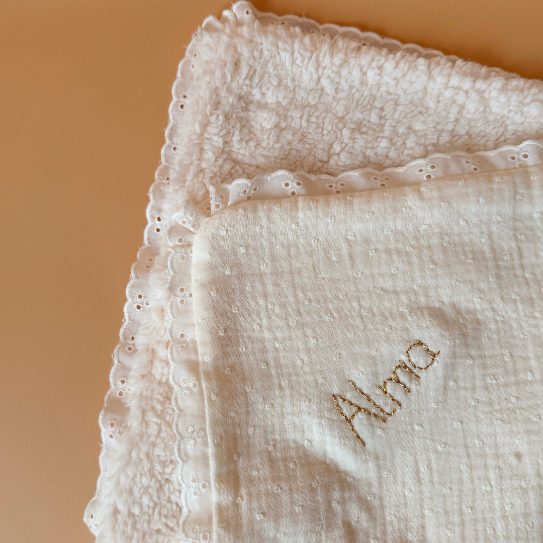 La couverture est une des pièces indispensable du trousseau de bébé. Parfaite en cadeau de naissance ou à s’offrir soit même, cette couverture demie saison est aprfaite pour accompagner bébé tout au long de l'année, Cette grande couverture pourra également être utilisée en descente de lit quand bébé sera plus grand. Cette couverture est idéale pour bien réchauffer les bébés en demie saison grâce à sa fausse fourrure type sherpa mouton beige , et sa doublure en gaze de coton hypoallergénique au magnifique mo