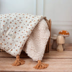 Découvrez la couverture pour bébé idéale pour apporter chaleur et douceur au quotidien de votre tout-petit ! Confectionnée à la main en France, cette couverture unique se compose d’une face au motif champignon enchanteur et d’une face en fausse fourrure sherpa beige extra douce, assurant confort et style. Pour un charme supplémentaire, quatre pompons couleur cassonade décorent élégamment chaque coin de la couverture. Et pour une touche encore plus personnelle, elle peut être brodée avec le prénom de votre b