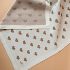 La couverture de naissance 12avril est bien plus qu’un simple accessoire : c’est un cocon de douceur et de chaleur, imaginé et tricoté avec soin en France, au cœur de la région roannaise, réputée pour son savoir-faire textile. Avec son motif all-over de petits cœurs biscuit délicatement posés sur un fond écru, elle séduit au premier regard par son esthétique tendre et intemporelle. Cette couverture est pensée pour réchauffer bébé tout en apportant une touche élégante et raffinée à sa chambre ou à vos sortie