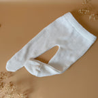 Offrez à votre bébé un premier vêtement doux, élégant et entièrement fabriqué en France avec cet adorable ensemble de naissance en maille blanche. Composé d'une brassière croisée et d'un pantalon assorti, cet ensemble est tricoté avec soin dans une maille jersey, un point traditionnel qui lui confère un relief raffiné et un toucher délicatement texturé. La brassière croisée s'attache facilement grâce à de petits boutons coloris bois, pour habiller bébé tout en douceur et sans effort. Le pantalon à taille él