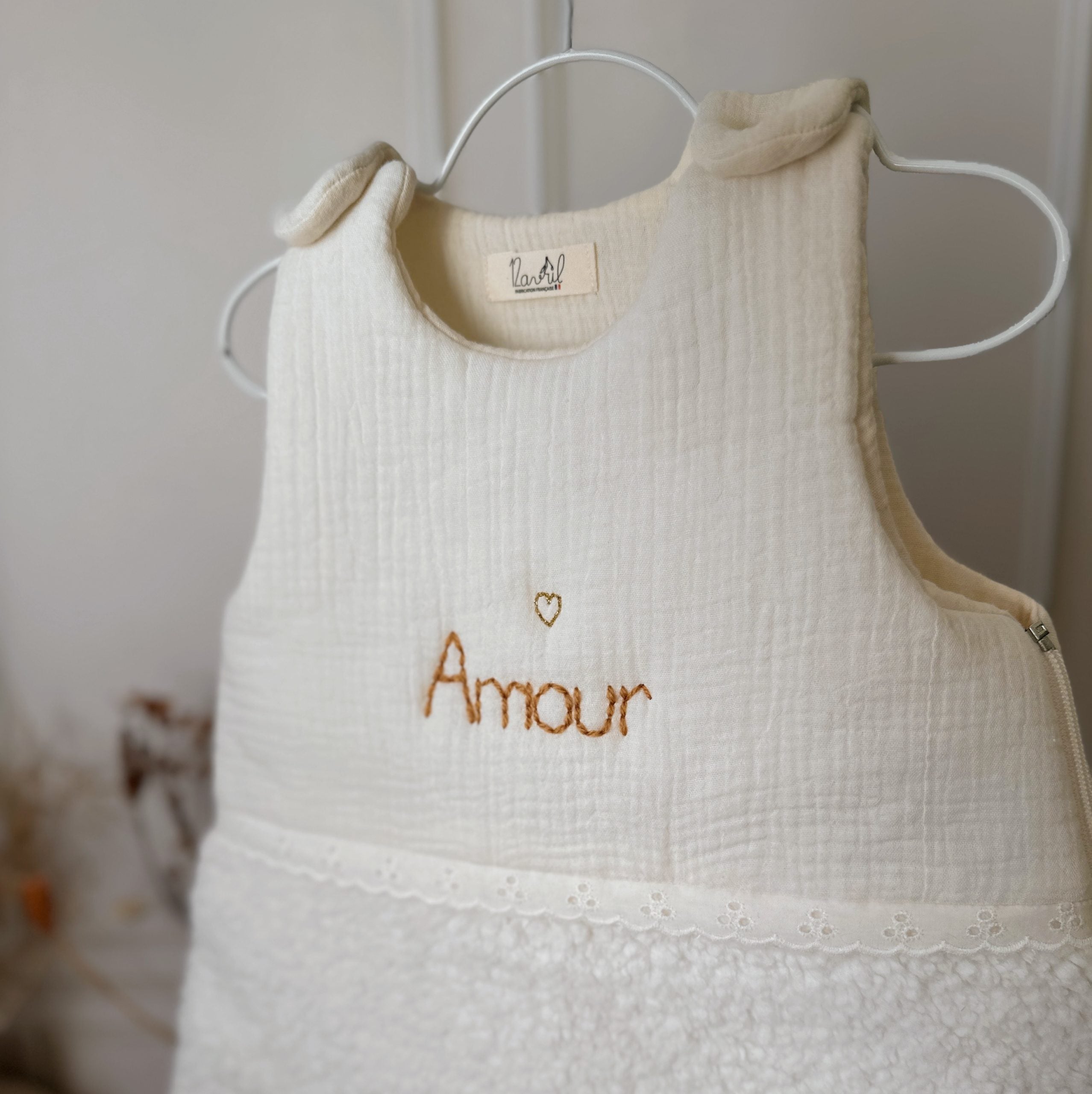 Cette gigoteuse pour bébé, confectionnée avec soin, est le choix idéal pour garder bébé au chaud durant l’hiver. Fabriquée en fausse fourrure type sherpa et en gaze de coton écrue, elle allie douceur et élégance. Son design raffiné, avec un empiècement en gaze de coton orné de délicate dentelle en broderie anglaise, en fait un accessoire de choix pour un sommeil cosy et stylé. Personnalisez la gigoteuse de bébé Vous avez la possibilité de personnaliser la gigoteuse avec le prénom ou le surnom de bébé, brodé