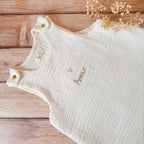 Gigoteuse d'Été en Triple Gaze de Coton Bio – Personnalisable Offrez à votre bébé un confort inégalé pendant les nuits d'été avec cette magnifique gigoteuse confectionnée dans une triple gaze de coton biologique certifiée Oeko-Tex, une matière d'exception bien plus douce et respirante que la traditionnelle double gaze. Sa texture gaufrée naturelle apporte douceur, légèreté et élégance. Disponible en coloris écru, cette gigoteuse est personnalisable au prénom de votre enfant, délicatement brodé sous un petit