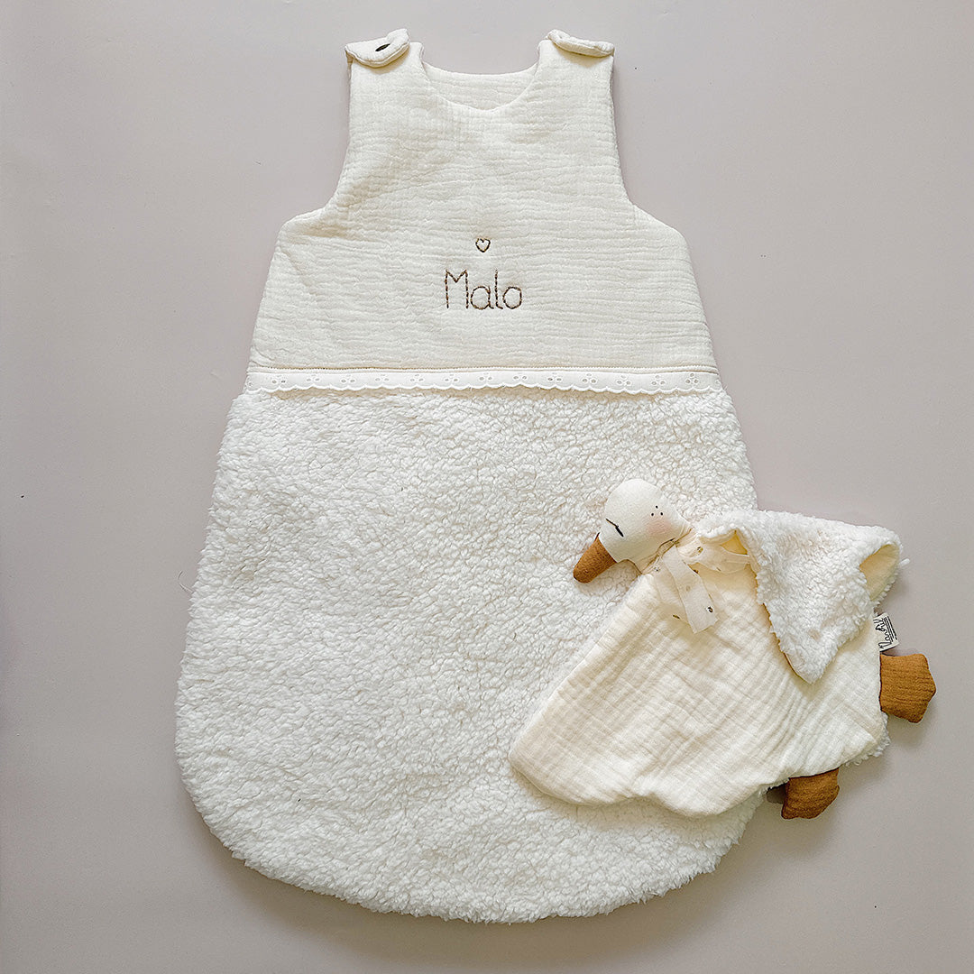 Cette gigoteuse pour bébé, confectionnée avec soin, est le choix idéal pour garder bébé au chaud durant l’hiver. Fabriquée en fausse fourrure type sherpa et en gaze de coton écrue, elle allie douceur et élégance. Son design raffiné, avec un empiècement en gaze de coton orné de délicate dentelle en broderie anglaise, en fait un accessoire de choix pour un sommeil cosy et stylé. Personnalisez la gigoteuse de bébé Vous avez la possibilité de personnaliser la gigoteuse avec le prénom ou le surnom de bébé, brodé