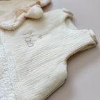 Cette gigoteuse pour bébé, confectionnée avec soin, est le choix idéal pour garder bébé au chaud durant l’hiver. Fabriquée en fausse fourrure type sherpa et en gaze de coton écrue, elle allie douceur et élégance. Son design raffiné, avec un empiècement en gaze de coton orné de délicate dentelle en broderie anglaise, en fait un accessoire de choix pour un sommeil cosy et stylé. Personnalisez la gigoteuse de bébé Vous avez la possibilité de personnaliser la gigoteuse avec le prénom ou le surnom de bébé, brodé