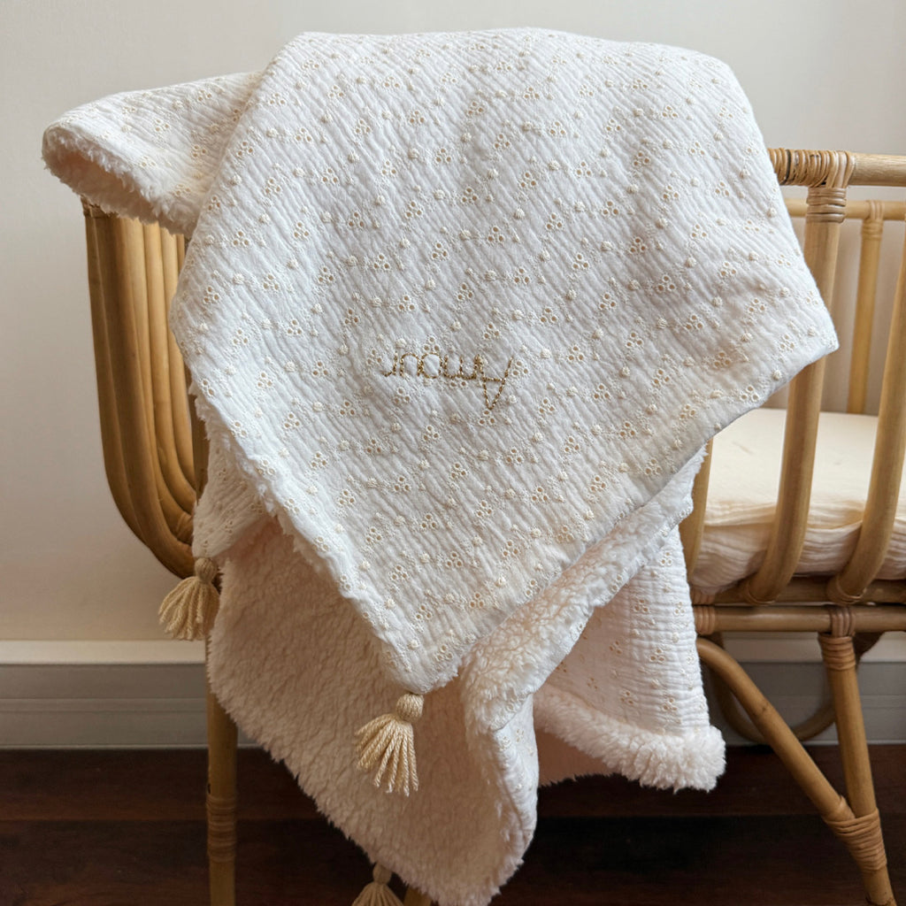 Apportez chaleur, tendresse et raffinement à votre quotidien avec cette magnifique couverture personnalisable, confectionnée avec soin en France. Un véritable cocon de douceur, pensé pour envelopper les petits et les grands dans un nuage de confort. Un textile d’exception, doux et élégant Cette grande couverture de 105 x 130 cm marie subtilement deux matières nobles et douces : Une face en gaze de coton brodée, inspirée de la broderie anglaise, légère et respirante, aux motifs floraux délicats qui évoquent 