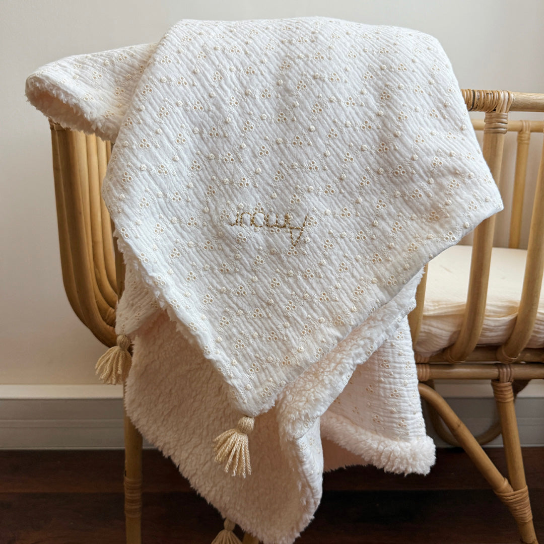 Apportez chaleur, tendresse et raffinement à votre quotidien avec cette magnifique couverture personnalisable, confectionnée avec soin en France. Un véritable cocon de douceur, pensé pour envelopper les petits et les grands dans un nuage de confort. Un textile d’exception, doux et élégant Cette grande couverture de 105 x 130 cm marie subtilement deux matières nobles et douces : Une face en gaze de coton brodée, inspirée de la broderie anglaise, légère et respirante, aux motifs floraux délicats qui évoquent 