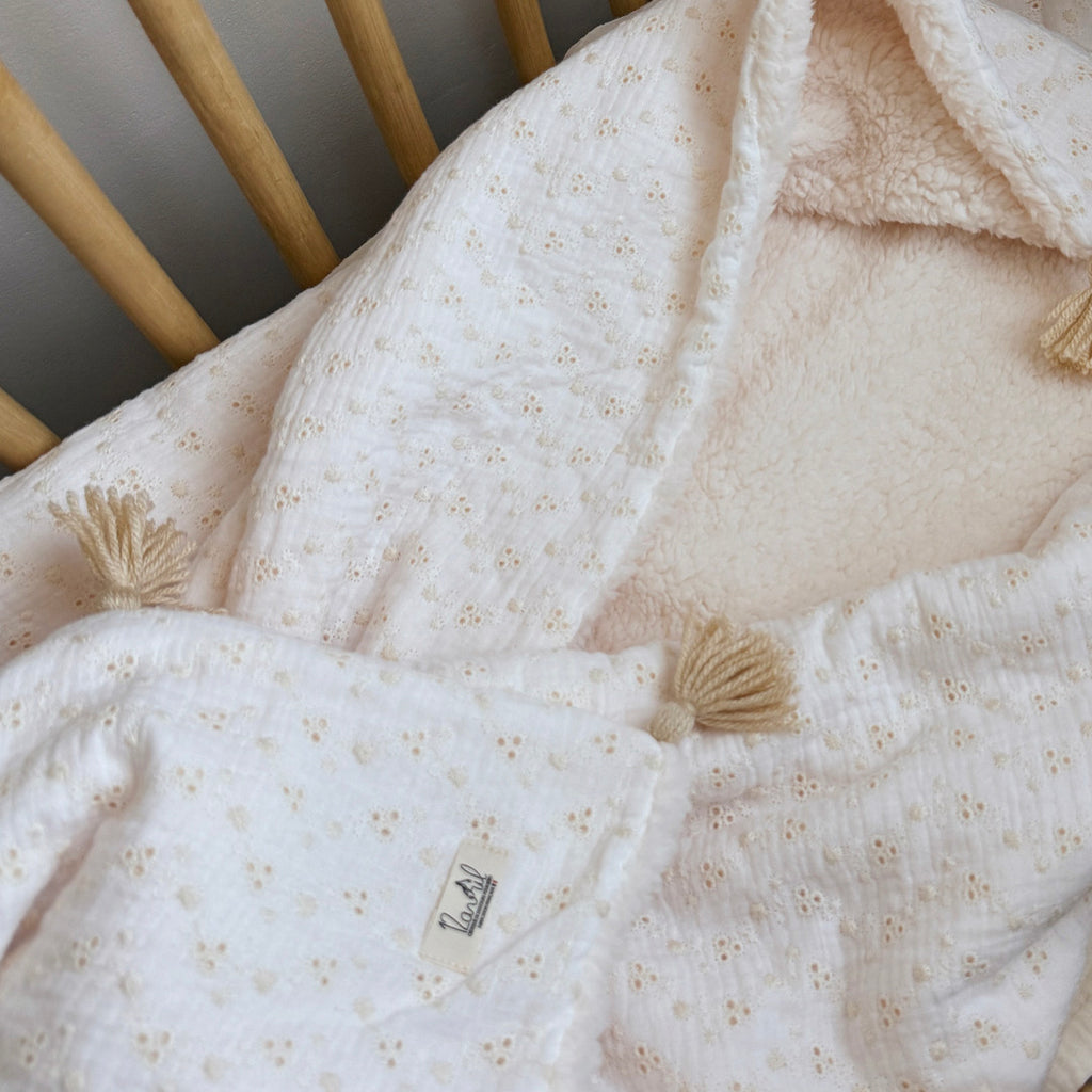 Apportez chaleur, tendresse et raffinement à votre quotidien avec cette magnifique couverture personnalisable, confectionnée avec soin en France. Un véritable cocon de douceur, pensé pour envelopper les petits et les grands dans un nuage de confort. Un textile d’exception, doux et élégant Cette grande couverture de 105 x 130 cm marie subtilement deux matières nobles et douces : Une face en gaze de coton brodée, inspirée de la broderie anglaise, légère et respirante, aux motifs floraux délicats qui évoquent 