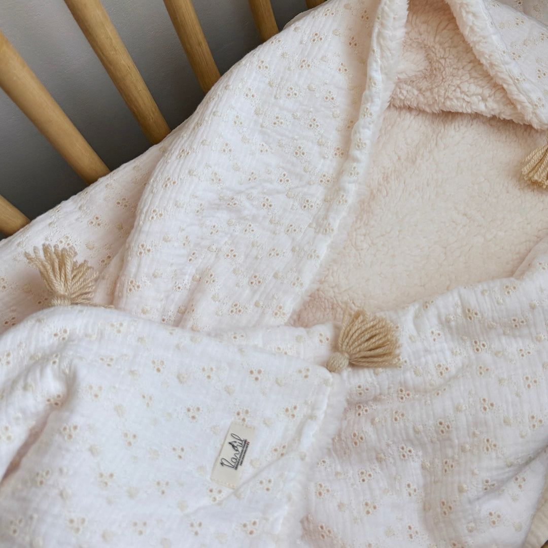 Apportez chaleur, tendresse et raffinement à votre quotidien avec cette magnifique couverture personnalisable, confectionnée avec soin en France. Un véritable cocon de douceur, pensé pour envelopper les petits et les grands dans un nuage de confort. Un textile d’exception, doux et élégant Cette grande couverture de 105 x 130 cm marie subtilement deux matières nobles et douces : Une face en gaze de coton brodée, inspirée de la broderie anglaise, légère et respirante, aux motifs floraux délicats qui évoquent 