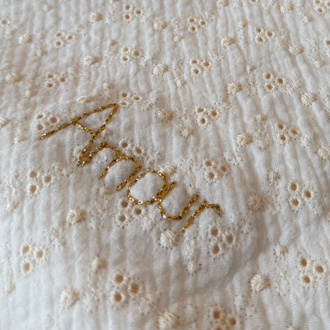 Apportez chaleur, tendresse et raffinement à votre quotidien avec cette magnifique couverture personnalisable, confectionnée avec soin en France. Un véritable cocon de douceur, pensé pour envelopper les petits et les grands dans un nuage de confort. Un textile d’exception, doux et élégant Cette grande couverture de 105 x 130 cm marie subtilement deux matières nobles et douces : Une face en gaze de coton brodée, inspirée de la broderie anglaise, légère et respirante, aux motifs floraux délicats qui évoquent 