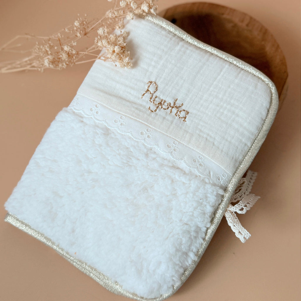 Pour protéger le carnet de santé tout en douceur et lui offrir une jolie enveloppe, voici l'accessoire qui rend les visites chez le médecin un peu plus gaies ! Fermeture au côté avec un joli lien en dentelle de coton.  Il est réalisé en fausse fourrure sherpa écrue avec notre jolie galon dentelle anglaise et gaze de coton. Son contour et biaisé par un ruban doré.