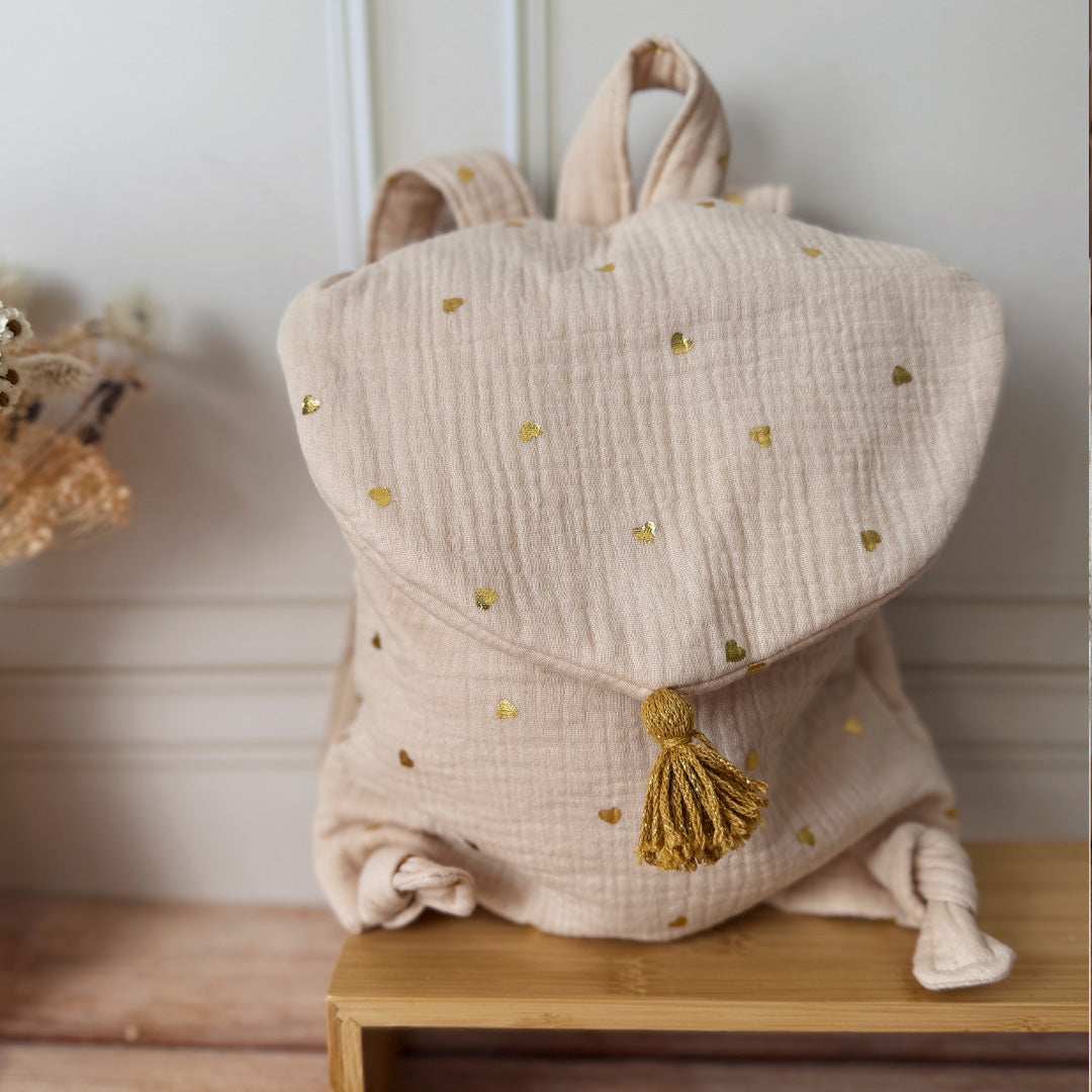 Adoptez notre tout nouveau sac à dos, il est idéal pour emporter le change, le biberon, la gourde, le départ pour la crèche, la nounou mais aussi les premiers pas pour l'école ! Il est tout doux, tout mou et tout léger pour prendre soin du dos de votre enfant. Il est réalisé en 100% gaze de coton ouatiné , dans nos ateliers français. Notre emblématique pompon vient habillé le petit rabat qui est lui même muni d'une pression. Les anses sont ajustables en réglant les petits nœuds.