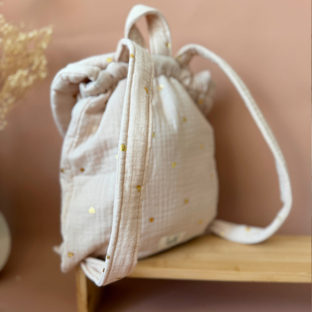 Adoptez notre tout nouveau sac à dos, il est idéal pour emporter le change, le biberon, la gourde, le départ pour la crèche, la nounou mais aussi les premiers pas pour l'école ! Il est tout doux, tout mou et tout léger pour prendre soin du dos de votre enfant. Il est réalisé en 100% gaze de coton ouatiné , dans nos ateliers français. Notre emblématique pompon vient habillé le petit rabat qui est lui même muni d'une pression. Les anses sont ajustables en réglant les petits nœuds.