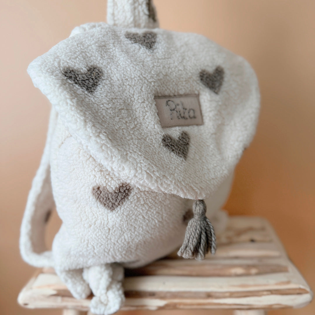 Adoptez notre tout nouveau sac à dos, il est idéal pour emporter le change, le biberon, la gourde, le départ pour la crèche, la nounou mais aussi les premiers pas pour l'école ! Il est tout doux, tout mou et tout léger pour prendre soin du dos de votre enfant. Il est réalisé en fausse fourrure sherpa,  ouatiné , dans nos ateliers français. Notre emblématique pompon vient habillé le petit rabat qui est lui même muni d'une pression. Les anses sont ajustables en réglant les petits nœuds. Fabriqué en sherpa  to