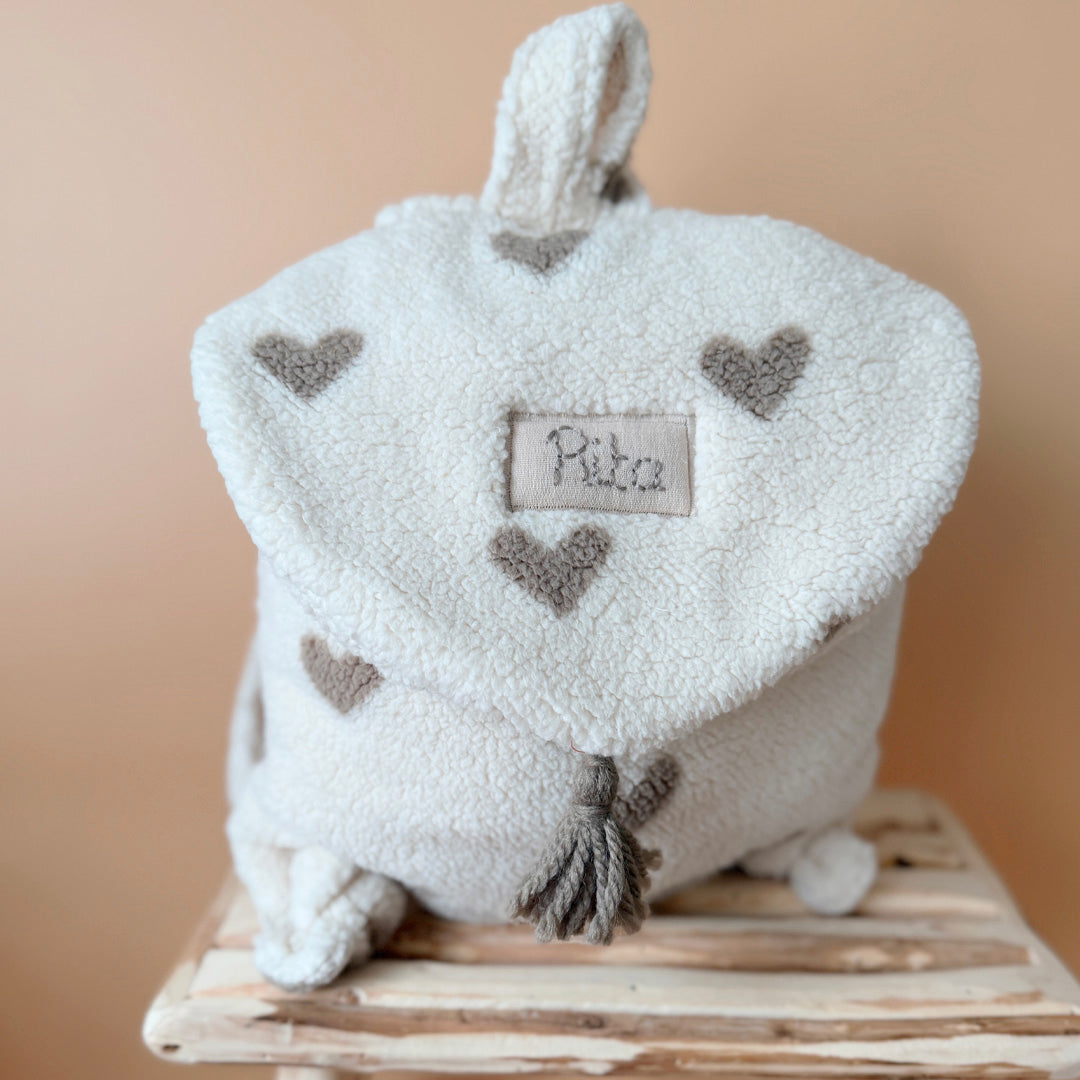 Adoptez notre tout nouveau sac à dos, il est idéal pour emporter le change, le biberon, la gourde, le départ pour la crèche, la nounou mais aussi les premiers pas pour l'école ! Il est tout doux, tout mou et tout léger pour prendre soin du dos de votre enfant. Il est réalisé en fausse fourrure sherpa,  ouatiné , dans nos ateliers français. Notre emblématique pompon vient habillé le petit rabat qui est lui même muni d'une pression. Les anses sont ajustables en réglant les petits nœuds. Fabriqué en sherpa  to