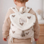 Adoptez notre tout nouveau sac à dos, il est idéal pour emporter le change, le biberon, la gourde, le départ pour la crèche, la nounou mais aussi les premiers pas pour l'école ! Il est tout doux, tout mou et tout léger pour prendre soin du dos de votre enfant. Il est réalisé en fausse fourrure sherpa,  ouatiné , dans nos ateliers français. Notre emblématique pompon vient habillé le petit rabat qui est lui même muni d'une pression. Les anses sont ajustables en réglant les petits nœuds. Fabriqué en sherpa  to