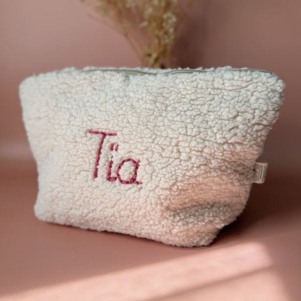 La trousse de toilette pour bébé est une pièce personnalisée et pratique, conçue avec soin pour répondre aux besoins des parents et de leur nouveau-né. Son grand format est très pratique.  La conception de la trousse permet aux produits de bébé de tenir debout à l'intérieur, ce qui facilite l'organisation et l'accès aux produits essentiels. Liniment, couches, lait de toilette, cotons, autant de produits pour un si petit bout de chou, que vous aurez besoin d'une grande trousse de toilette spacieuse. Fabriquée en fausse fourrure sherpa beige, cette trousse est à la fois douce et durable. L'intérieur de la trousse est doublé avec un tissu imperméable. Ls liquides renversés ne pénètrent pas à l'extérieur, protégeant ainsi les autres articles dans le sac à langer. Personnaliser votre trousse de toilette, au doux prénom de bébé ! La personnalisation est réalisée à la main sur le devant de la trousse de toilette avec un fil du coloris de votre choix. 3 petites étoiles dorées entourent le prénom. Fièrement fabriquée en France, cette trousse de toilette est le fruit d'un savoir-faire artisanal et d'une attention particulière aux détails. Zoom sur le petit curseur de la fermeture à glissière ! Découvrez notre gamme entière de produits autour du bain : de belles et grandes capes de bain XXL, langes et débarbouillettes. 