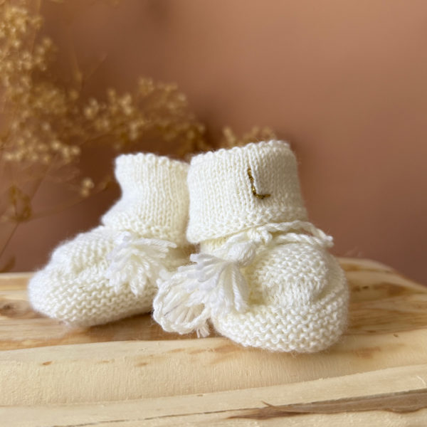 Les premiers jours de bébé sont précieux, et chaque détail compte pour assurer son confort et sa chaleur. Les chaussons en maille tricto réchaufferont les petits pieds de votre tout-petit pour ces premiers jours. Tricoté avec soin cette laine apporte de la chaleur, une légèreté, un fil chaud , doux et léger. Ils sont fabriqués dans l’un de nos ateliers partenaires français. Un cadeau parfaitement adapté pour accueillir votre petit trésor dans le monde avec tendresse et douceur. Grâce à sa texture et à sa conception, nos chaussons de naissance maintiennent la chaleur corporelle de votre bébé au niveau de ces petits pieds.  Offrez à votre bébé le confort et la chaleur dont il a besoin  en complétant son trousseau de naissance avec un petit bonnet. Un cadeau parfaitement adapté pour accueillir votre petit trésor dans le monde avec tendresse et douceur. Vous pouvez également compléter ce petit look de naissance avec l’une de nos brassières douce et chaude en maille.