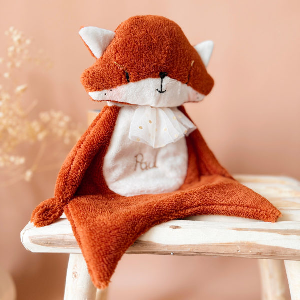 Optez pour le charmant doudou renard, parfait compagnon pour partager des instants doux et câlins avec votre bébé. Ce premier compagnon lui procurera une sensation de douceur et d'émerveillement, en faisant un cadeau idéal pour une naissance. Bébé appréciera la variété des matières afin de développer au mieux sa motricité fine. Le doudou Renard appelé Mr Renardeau est composé de 2 différents tissus : une micro éponge de bambou terracotta, idéale pour absorber les chagrins de bébé grâce à son séchage naturel rapide et son haut pouvoir absorbant. une fine fausse fourrure plate écrue , où nous pouvons venir broder le prénom de votre enfant. Tous les éléments sont brodés et pris en couture pour un maximum de solidité.