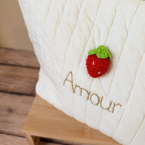 Apportez une touche de tendresse à vos accessoires avec cette trousse de toilette matelassée en jersey de coton, entièrement confectionnée en France. Pensée pour les mamans, les enfants ou tout simplement pour se faire plaisir, cette trousse incarne à la fois le charme artisanal et la fonctionnalité. Son tissu matelassé lui confère une allure douce et moelleuse, parfaite pour y glisser les essentiels de toilette ou les petits trésors du quotidien. Ce qui la rend unique ? Sa jolie fraise en crochet rouge cousue sur le devant, associée à une broderie dorée personnalisée au prénom de votre choix. Chaque trousse est brodée à la main avec soin, rendant chaque pièce unique et affectueuse. Idéale comme cadeau de naissance, de babyshower, ou pour toute occasion où l’on veut faire plaisir avec du fait-main de qualité.