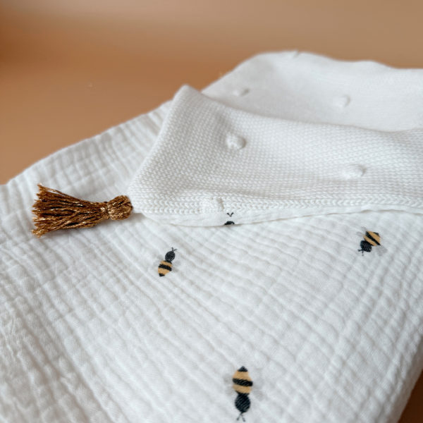 Parce qu’il est important de couvrir bébé même l’été, nous avons développé cette couverture 100% coton. Dès son arrivée, bébé passe d'un environnement clos de 37°C à une température extérieure que l’on ne peut pas toujours contrôler. En sortie avec un petit bébé d’été, vous pourriez vite être incommodés par un climatiseur. Bébé sera sensible aux petits coups de vent ou aux changements de températures en soirée. Bébé aura besoin également d’être tenu au chaud pendant la sieste (la température du corps descend lorsque nous dormons et sommes immobiles). C’est pour cela que nous avons conçu cette grande couverture d’été respirante, douce et hypoallergénique. Retrouvez notre gamme complète de couvertures d'été personnalisées. Ni trop légère ni trop chaude, elle est idéale pour réchauffer bébé de manière naturelle grâce à sa composition en gaze de coton (100%) Oeko-Tex et en maille de coton avec ces jolis petits pois en relief,  ce qui assure une vraie respiration cutanée. Comme toutes nos couvertures elle est très souple et enveloppera parfaitement bébé.