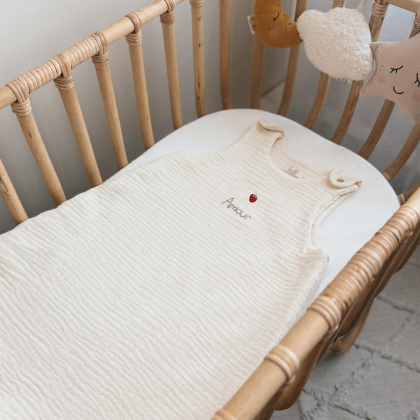 Offrez à votre bébé un confort inégalé pendant les nuits d'été avec cette magnifique gigoteuse confectionnée dans une triple gaze de coton biologique certifiée Oeko-Tex, une matière d'exception bien plus douce et respirante que la traditionnelle double gaze. Sa texture gaufrée naturelle apporte douceur, légèreté et élégance. Disponible en coloris écru, cette gigoteuse est personnalisable au prénom de votre enfant, délicatement brodé sous une petite fraise appliquée au centre, ajoutant une touche fruitée et unique. Conçue pour faciliter le quotidien des parents, elle s'ouvre aisément grâce à deux pressions dorées aux épaules et une grande fermeture à glissière latérale, permettant un habillage simple et rapide, même lorsque bébé dort. Un véritable cocon de tendresse, pensé pour le bien-être des tout-petits et la tranquillité des grands.