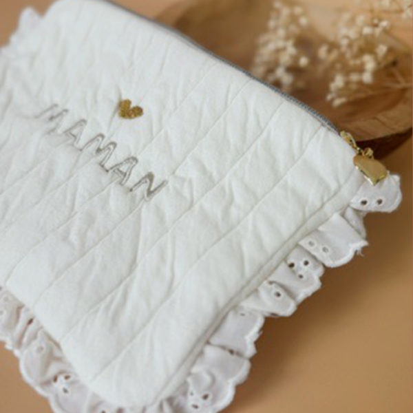 Apportez une touche de tendresse à vos accessoires avec cette trousse  matelassée en jersey de coton, entièrement confectionnée en France. Pensée pour les mamans, les enfants ou tout simplement pour se faire plaisir, cette trousse incarne à la fois le charme artisanal et la fonctionnalité. Son tissu matelassé lui confère une allure douce et moelleuse, parfaite pour y glisser les essentiels de toilette ou les petits trésors du quotidien. Ce qui la rend unique ? Sa jolie broderie Maman , effectuée sur le devant de la trousse.  Idéale comme cadeau de naissance, de babyshower, ou pour toute occasion où l’on veut faire plaisir avec du fait-main de qualité. Fièrement fabriquée en France, cette trousse de toilette est le fruit d'un savoir-faire artisanal et d'une attention particulière aux détails. Zoom sur le petit curseur de la fermeture à glissière !
