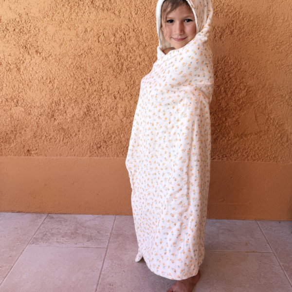 Faites de chaque moment de bain un moment de douceur et de confort pour votre tout-petit avec notre cape de bain XXL. Grâce à son maxi format, elle convient pour les enfants de 0 à 5 ans. Fabriquée en France avec une micro-éponge de bambou écrue de qualité supérieure, cette cape offre une absorption optimale et une sensation de luxe à chaque utilisation. Cette cape de bain généreuse est conçue pour envelopper confortablement votre bébé, offrant une couverture totale. Ainsi votre enfant est bien enveloppé à la sortie du bain tout en favorisant sa chaleur corporelle après le bain. La capuche intégrée permet de garder la tête de votre bébé au chaud et offre un séchage rapide des cheveux. Agrémentée d'un doux imprimé aux motifs estivaux, cette cape de bain apporte une touche de fraîcheur et de gaieté à l'heure du bain. Grâce à la matière en micro-éponge de bambou, cette matière naturelle est douce pour la peau délicate de votre bébé.  Elle est également très absorbante et respectueuse de l'environnement.
