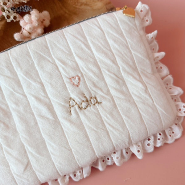 Apportez une touche de tendresse à vos accessoires avec cette trousse  matelassée en jersey de coton, entièrement confectionnée en France. Pensée pour les mamans, les enfants ou tout simplement pour se faire plaisir, cette trousse incarne à la fois le charme artisanal et la fonctionnalité. Son tissu matelassé lui confère une allure douce et moelleuse, parfaite pour y glisser les essentiels de toilette ou les petits trésors du quotidien. Ce qui la rend unique ? Sa jolie broderie Maman , effectuée sur le devant de la trousse.  Idéale comme cadeau de naissance, de babyshower, ou pour toute occasion où l’on veut faire plaisir avec du fait-main de qualité. Fièrement fabriquée en France, cette trousse de toilette est le fruit d'un savoir-faire artisanal et d'une attention particulière aux détails. Zoom sur le petit curseur de la fermeture à glissière !