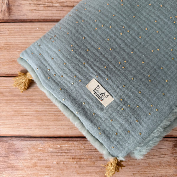 La couverture est une des pièces indispensable du trousseau de bébé. Parfaite en cadeau de naissance ou à s’offrir soit même, cette couverture chaude spéciale “bébés d’hiver”, vous accompagnera très longtemps dans vos moments câlins avec bébé. Les bébés d’hiver qui naissent pendant les mois les plus froids ont besoin d'être tenus bien au chaud à la sortie du ventre de maman. C'est pourquoi nous avons conçu cette couverture chaude spéciale “bébé d’hiver”. Dès son arrivée, bébé passe d'un environnement clos de 37°C à une température extérieure souvent très basse en hiver. C'est pour cela que nos couvertures d'hiver sont idéales pour réguler et maintenir une bonne température pour le corps de bébé.  Cette grande couverture pourra également être utilisée en descente de lit quand bébé sera plus grand. Cette couverture est idéale pour bien réchauffer les bébés d’hiver grâce à sa fausse fourrure extra douce, très épaisse (365g/m2), et sa doublure en gaze de coton hypoallergénique au magnifique motif d'un doux feuillage et de petites hirondelles. Un motif doux et unisexe. Quatre pompons en laine doré viennent sublimer la couverture dans les angles. Ils sont fabriqués à la main pour une pièce encore plus unique. Chaque pompon est posé très fermement avec des points solides afin de garantir une sécurité optimale pour votre enfant.