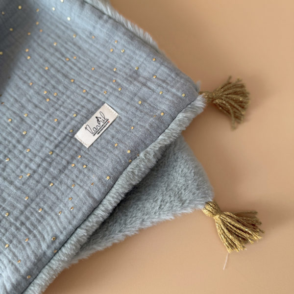 La couverture est une des pièces indispensable du trousseau de bébé. Parfaite en cadeau de naissance ou à s’offrir soit même, cette couverture chaude spéciale “bébés d’hiver”, vous accompagnera très longtemps dans vos moments câlins avec bébé. Les bébés d’hiver qui naissent pendant les mois les plus froids ont besoin d'être tenus bien au chaud à la sortie du ventre de maman. C'est pourquoi nous avons conçu cette couverture chaude spéciale “bébé d’hiver”. Dès son arrivée, bébé passe d'un environnement clos de 37°C à une température extérieure souvent très basse en hiver. C'est pour cela que nos couvertures d'hiver sont idéales pour réguler et maintenir une bonne température pour le corps de bébé.  Cette grande couverture pourra également être utilisée en descente de lit quand bébé sera plus grand. Cette couverture est idéale pour bien réchauffer les bébés d’hiver grâce à sa fausse fourrure extra douce, très épaisse (365g/m2), et sa doublure en gaze de coton hypoallergénique au magnifique motif d'un doux feuillage et de petites hirondelles. Un motif doux et unisexe. Quatre pompons en laine doré viennent sublimer la couverture dans les angles. Ils sont fabriqués à la main pour une pièce encore plus unique. Chaque pompon est posé très fermement avec des points solides afin de garantir une sécurité optimale pour votre enfant.