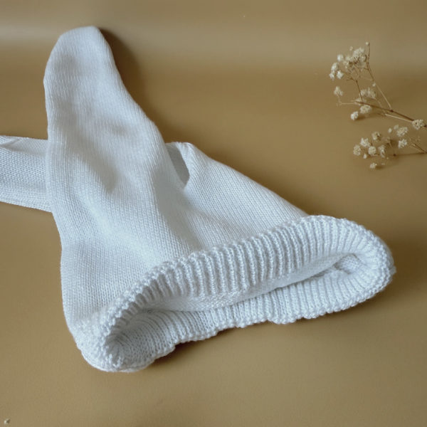Offrez à votre bébé un premier vêtement doux, élégant et entièrement fabriqué en France avec cet adorable ensemble de naissance en maille blanche. Composé d'une brassière croisée et d'un pantalon assorti, cet ensemble est tricoté avec soin dans une maille jersey, un point traditionnel qui lui confère un relief raffiné et un toucher délicatement texturé. La brassière croisée s'attache facilement grâce à de petits boutons coloris bois, pour habiller bébé tout en douceur et sans effort. Le pantalon à taille élastiquée et à pieds  assure un confort optimal et un bon maintien, sans comprimer le ventre fragile des nouveau-nés. Ce modèle est intégralement tricoté en France, en collaboration avec un atelier partenaire reconnu pour son savoir-faire en maille fine pour bébé. Une attention toute particulière est portée à la qualité des finitions, pour un rendu chic, intemporel et parfaitement adapté à la peau des tout-petits. Et pour rendre ce cadeau de naissance encore plus unique, vous pouvez choisir de personnaliser la brassière avec une broderie faite main, directement au centre du vêtement. Que ce soit le prénom du bébé ou un petit mot doux, chaque pièce devient ainsi un souvenir précieux, plein d’émotion.