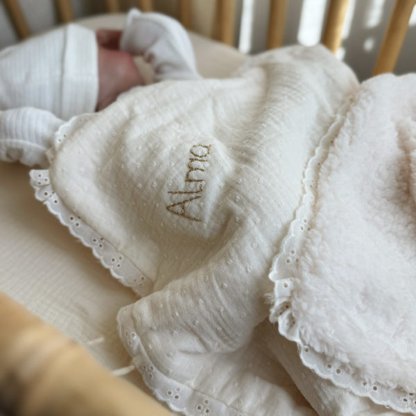 La couverture est une des pièces indispensable du trousseau de bébé. Parfaite en cadeau de naissance ou à s’offrir soit même, cette couverture demie saison est aprfaite pour accompagner bébé tout au long de l'année, Cette grande couverture pourra également être utilisée en descente de lit quand bébé sera plus grand. Cette couverture est idéale pour bien réchauffer les bébés en demie saison grâce à sa fausse fourrure type sherpa mouton beige , et sa doublure en gaze de coton hypoallergénique au magnifique motif de petits oiseaux inséparables façon toile de Jouy. Un motif doux et unisexe. Une magnifique dentelle vient sublimer le contour de la couverture.