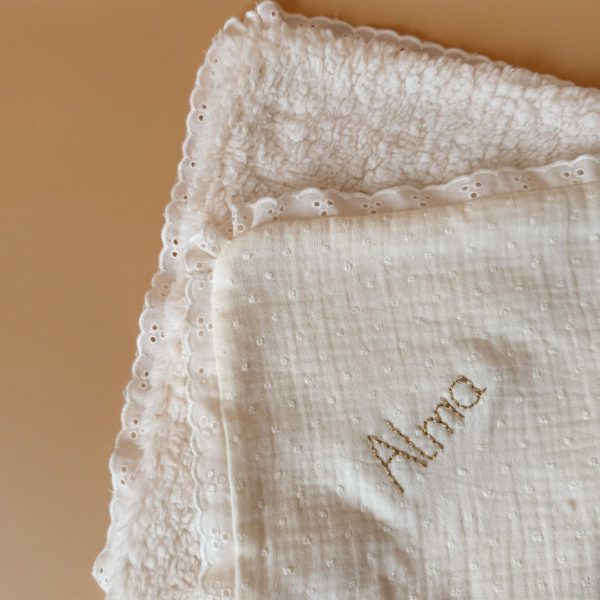 La couverture est une des pièces indispensable du trousseau de bébé. Parfaite en cadeau de naissance ou à s’offrir soit même, cette couverture demie saison est aprfaite pour accompagner bébé tout au long de l'année, Cette grande couverture pourra également être utilisée en descente de lit quand bébé sera plus grand. Cette couverture est idéale pour bien réchauffer les bébés en demie saison grâce à sa fausse fourrure type sherpa mouton beige , et sa doublure en gaze de coton hypoallergénique au magnifique motif de petits oiseaux inséparables façon toile de Jouy. Un motif doux et unisexe. Une magnifique dentelle vient sublimer le contour de la couverture.