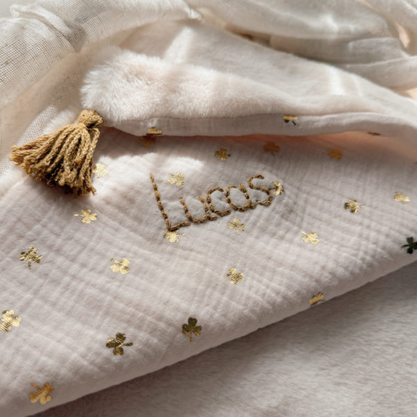La couverture est une des pièces indispensable du trousseau de bébé. Parfaite en cadeau de naissance ou à s’offrir soit même, cette couverture chaude spéciale “bébés d’hiver”, vous accompagnera très longtemps dans vos moments câlins avec bébé. Les bébés d’hiver qui naissent pendant les mois les plus froids ont besoin d'être tenus bien au chaud à la sortie du ventre de maman. C'est pourquoi nous avons conçu cette couverture chaude spéciale “bébé d’hiver”. Dès son arrivée, bébé passe d'un environnement clos de 37°C à une température extérieure souvent très basse en hiver. C'est pour cela que nos couvertures d'hiver épaisses sont idéales pour réguler et maintenir une bonne température pour le corps de bébé. Comme toutes nos couvertures elle est très souple et enveloppera parfaitement bébé. Cette grande couverture pourra également être utilisée en descente de lit quand bébé sera plus grand. Cette couverture est idéale pour bien réchauffer les bébés d’hiver grâce à sa fausse fourrure extra douce grège, très épaisse (365g/m2), et sa doublure en gaze de coton hypoallergénique au joli petit motif trèfles dorés, un motif plein de sens parfois pour certaines histoires ...  Quatre pompons en laine  dorée viennent sublimer la couverture dans les angles. Ils sont fabriqués à la main pour une pièce encore plus unique. Chaque pompon est posé très fermement avec des points solides afin de garantir une sécurité optimale pour votre enfant.