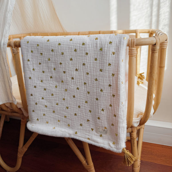La couverture est une des pièces indispensable du trousseau de bébé. Parfaite en cadeau de naissance ou à s’offrir soit même, cette couverture chaude spéciale “bébés d’hiver”, vous accompagnera très longtemps dans vos moments câlins avec bébé. Les bébés d’hiver qui naissent pendant les mois les plus froids ont besoin d'être tenus bien au chaud à la sortie du ventre de maman. C'est pourquoi nous avons conçu cette couverture chaude spéciale “bébé d’hiver”. Dès son arrivée, bébé passe d'un environnement clos de 37°C à une température extérieure souvent très basse en hiver. C'est pour cela que nos couvertures d'hiver épaisses sont idéales pour réguler et maintenir une bonne température pour le corps de bébé. Comme toutes nos couvertures elle est très souple et enveloppera parfaitement bébé. Cette grande couverture pourra également être utilisée en descente de lit quand bébé sera plus grand. Cette couverture est idéale pour bien réchauffer les bébés d’hiver grâce à sa fausse fourrure extra douce grège, très épaisse (365g/m2), et sa doublure en gaze de coton hypoallergénique au joli petit motif trèfles dorés, un motif plein de sens parfois pour certaines histoires ...  Quatre pompons en laine  dorée viennent sublimer la couverture dans les angles. Ils sont fabriqués à la main pour une pièce encore plus unique. Chaque pompon est posé très fermement avec des points solides afin de garantir une sécurité optimale pour votre enfant.