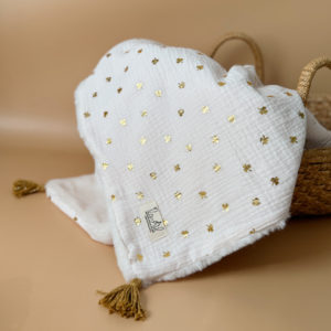 La couverture est une des pièces indispensable du trousseau de bébé. Parfaite en cadeau de naissance ou à s’offrir soit même, cette couverture chaude spéciale “bébés d’hiver”, vous accompagnera très longtemps dans vos moments câlins avec bébé. Les bébés d’hiver qui naissent pendant les mois les plus froids ont besoin d'être tenus bien au chaud à la sortie du ventre de maman. C'est pourquoi nous avons conçu cette couverture chaude spéciale “bébé d’hiver”. Dès son arrivée, bébé passe d'un environnement clos de 37°C à une température extérieure souvent très basse en hiver. C'est pour cela que nos couvertures d'hiver épaisses sont idéales pour réguler et maintenir une bonne température pour le corps de bébé. Comme toutes nos couvertures elle est très souple et enveloppera parfaitement bébé. Cette grande couverture pourra également être utilisée en descente de lit quand bébé sera plus grand. Cette couverture est idéale pour bien réchauffer les bébés d’hiver grâce à sa fausse fourrure extra douce grège, très épaisse (365g/m2), et sa doublure en gaze de coton hypoallergénique au joli petit motif trèfles dorés, un motif plein de sens parfois pour certaines histoires ...  Quatre pompons en laine  dorée viennent sublimer la couverture dans les angles. Ils sont fabriqués à la main pour une pièce encore plus unique. Chaque pompon est posé très fermement avec des points solides afin de garantir une sécurité optimale pour votre enfant.