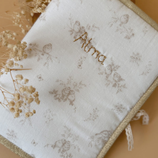 Pour protéger le carnet de santé tout en douceur et lui offrir une jolie enveloppe, voici l'accessoire qui rend les visites chez le médecin un peu plus gaies ! Fermeture au côté avec un joli lien en dentelle de coton. Il est réalisé dans notre joli motif unisexe Oiseaux Inséparables légèrement rembourré et biaisé par un ruban beige doré. Caractéristiques techniques  Made In France : tricoté en France dans la région roannaise Dimension : Taille standard A5 - 24 x 17 cm - 100% gaze de coton Matières :   100% gaze de coton, rembourrage 100% polyester Coloris : motif oiseaux inséparables Personnalisation : broderie faite à la main  Conseil d'entretien : lavage à la main ou lavage en machine, programme délicat à froid, lavage à 30° maximum | Pas de séchage en machine. Délais de fabrication : 8/10 jours ouvrés (3/5 jours ouvrés sans personnalisation). Option “commande urgente” à 15€ (fabrication et livraison en 8 jours ouvrés chez vous avec colissimo uniquement).  Délais de livraison : 48h en colissimo ; 3 à 6 jours ouvrés par Mondial Relay ; 48h en lettre suivie