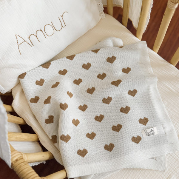 La couverture de naissance 12avril est bien plus qu’un simple accessoire : c’est un cocon de douceur et de chaleur, imaginé et tricoté avec soin en France, au cœur de la région roannaise, réputée pour son savoir-faire textile. Avec son motif all-over de petits cœurs biscuit délicatement posés sur un fond écru, elle séduit au premier regard par son esthétique tendre et intemporelle. Cette couverture est pensée pour réchauffer bébé tout en apportant une touche élégante et raffinée à sa chambre ou à vos sorties. Conçue à partir d’un fil de qualité, composé à 50% de laine, elle offre la chaleur idéale pour l’hiver tout en restant respirante. Sa texture tricotée apporte un confort douillet et une grande souplesse, parfaite pour envelopper bébé lors des siestes, des promenades ou des moments de tendresse à la maison. De forme carrée (80 x 80 cm), elle est parfaitement adaptée aux tout-petits : facile à plier, à transporter et à utiliser dans un berceau, une poussette ou un siège-auto. Elle accompagnera bébé partout, dès la naissance, en offrant une sensation rassurante de cocon et de sécurité. Chaque couverture est le fruit d’une confection locale, valorisant le savoir-faire français et une production respectueuse. C’est un cadeau de naissance idéal, qui allie esthétisme, praticité et authenticité. Offrir ou s’offrir la couverture de naissance 12avril, c’est choisir un produit de caractère, plein de tendresse, pensé pour durer et transmettre la chaleur de l’amour dès les premiers jours de vie.